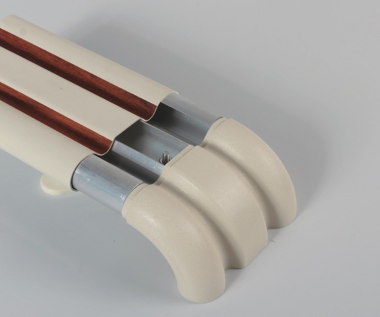 A white toilet seat with a wooden handle and PVC hand rails.