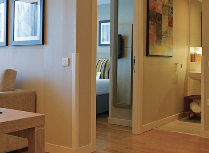 A living room with a couch and tv, furnished with wood corner guards for added protection.