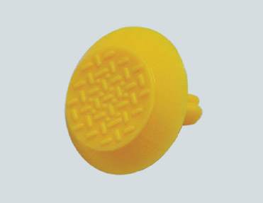 A yellow plastic button on a white background surrounded by stainless steel studs.