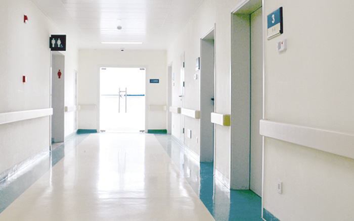 A long hallway in a hospital with PVC wall guards and handrails.