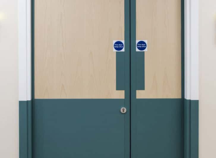 A hospital room with blue and green wall panels and PVC wall guards.