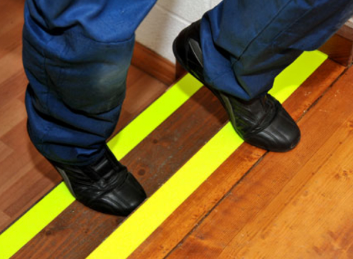A person's feet on a yellow antislip tape.