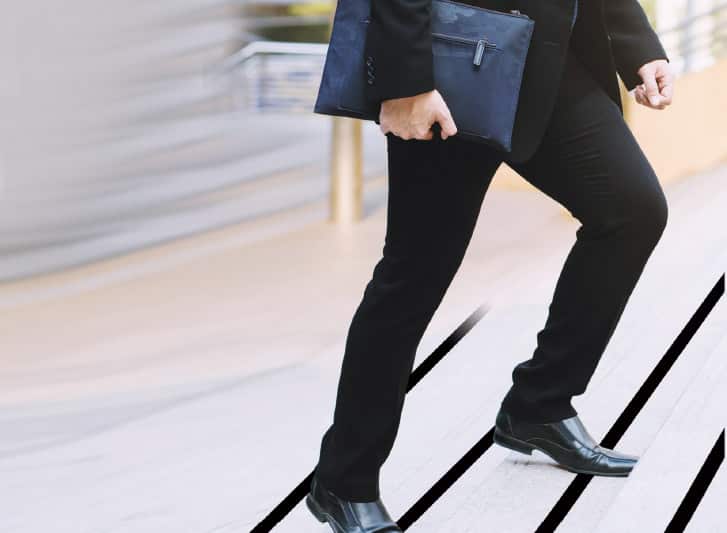 A man in a suit walking down a stairway, ensuring his safety with antislip tape.