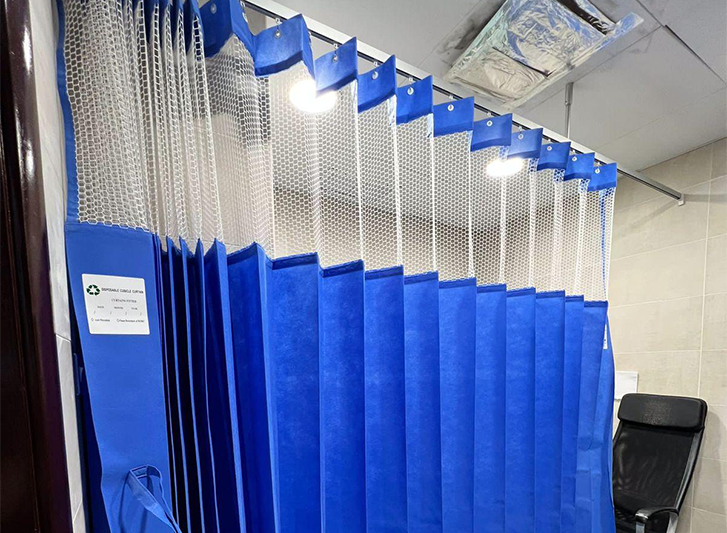 A blue shower curtain hanging in a bathroom with curtain rails.