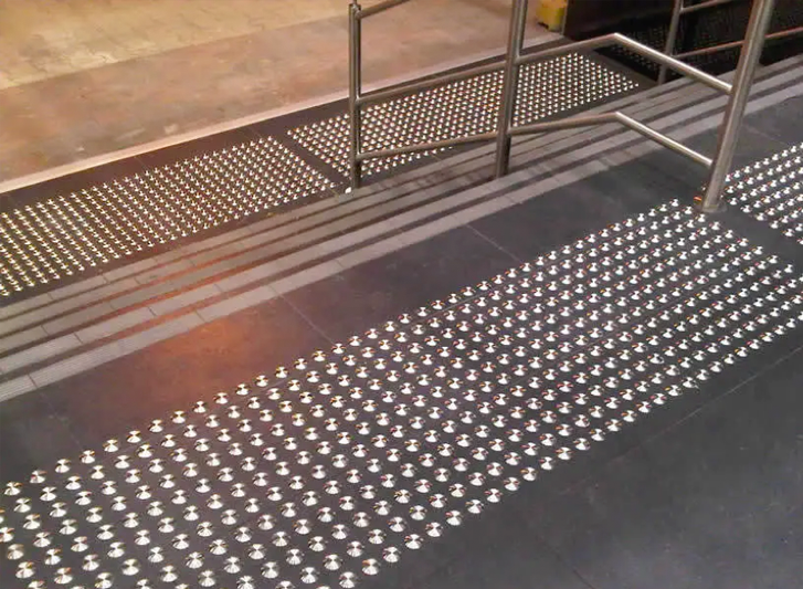 A metal stair tread with a stainless steel railing.