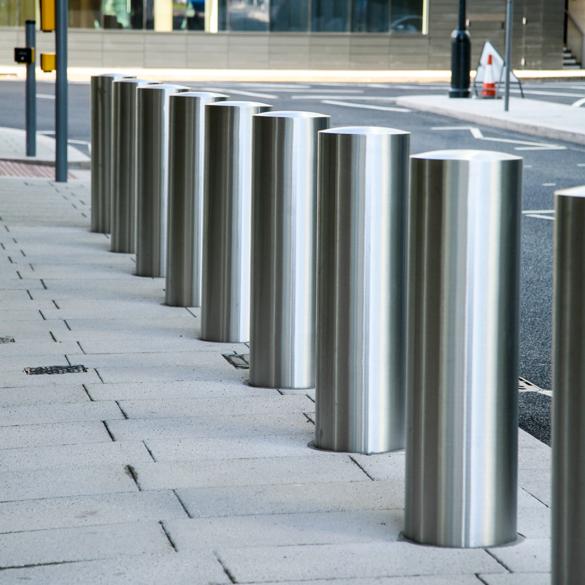 A row of stainless steel bollards on a sidewalk.