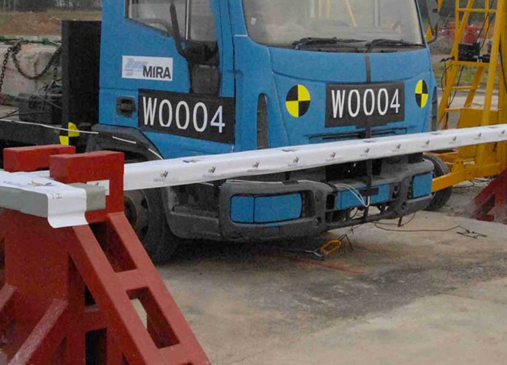 A blue truck is parked next to a stainless steel barrier.
