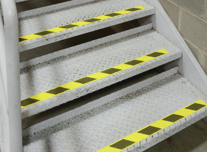 A set of stairs with vibrant yellow and black stripes enhanced with antislip tape.