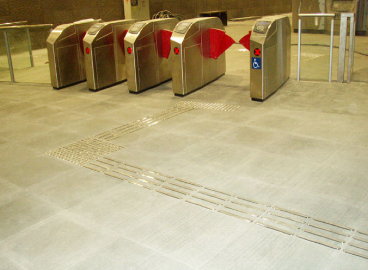 A line of ticket machines in a subway station equipped with stainless steel studs and strips.