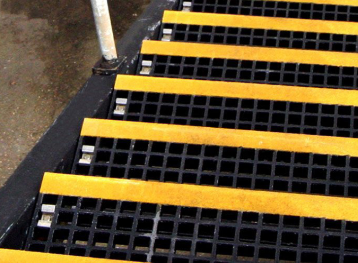 A close up of a yellow aluminium stair nosing grate on a stair.
