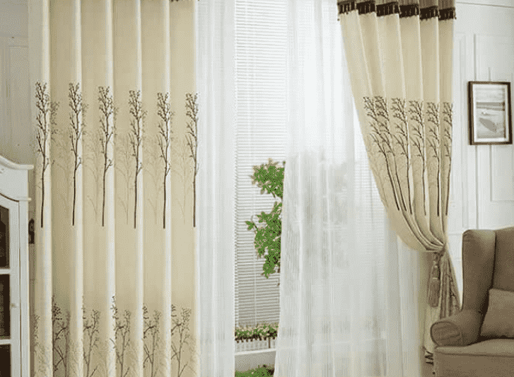 A living room with beige curtains and a chair.