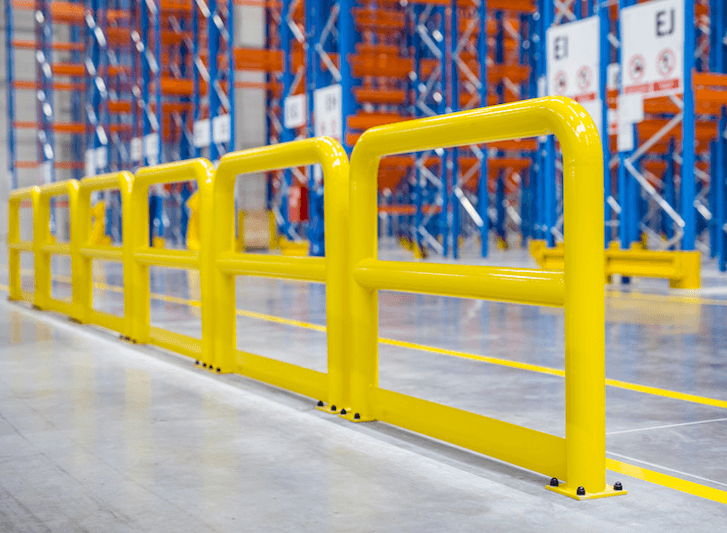 A yellow barrier in a warehouse, reinforced with stainless steel bollards or crash bollards.