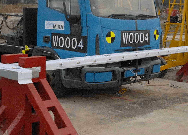 A blue truck is parked next to a stainless steel barrier.